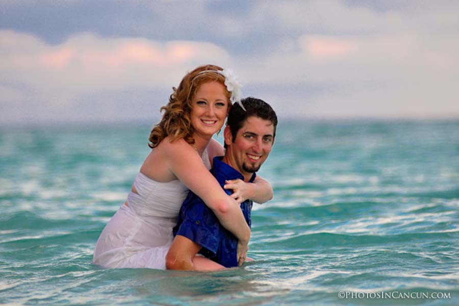 a couple stand in the water for the trash the dress at the ocean